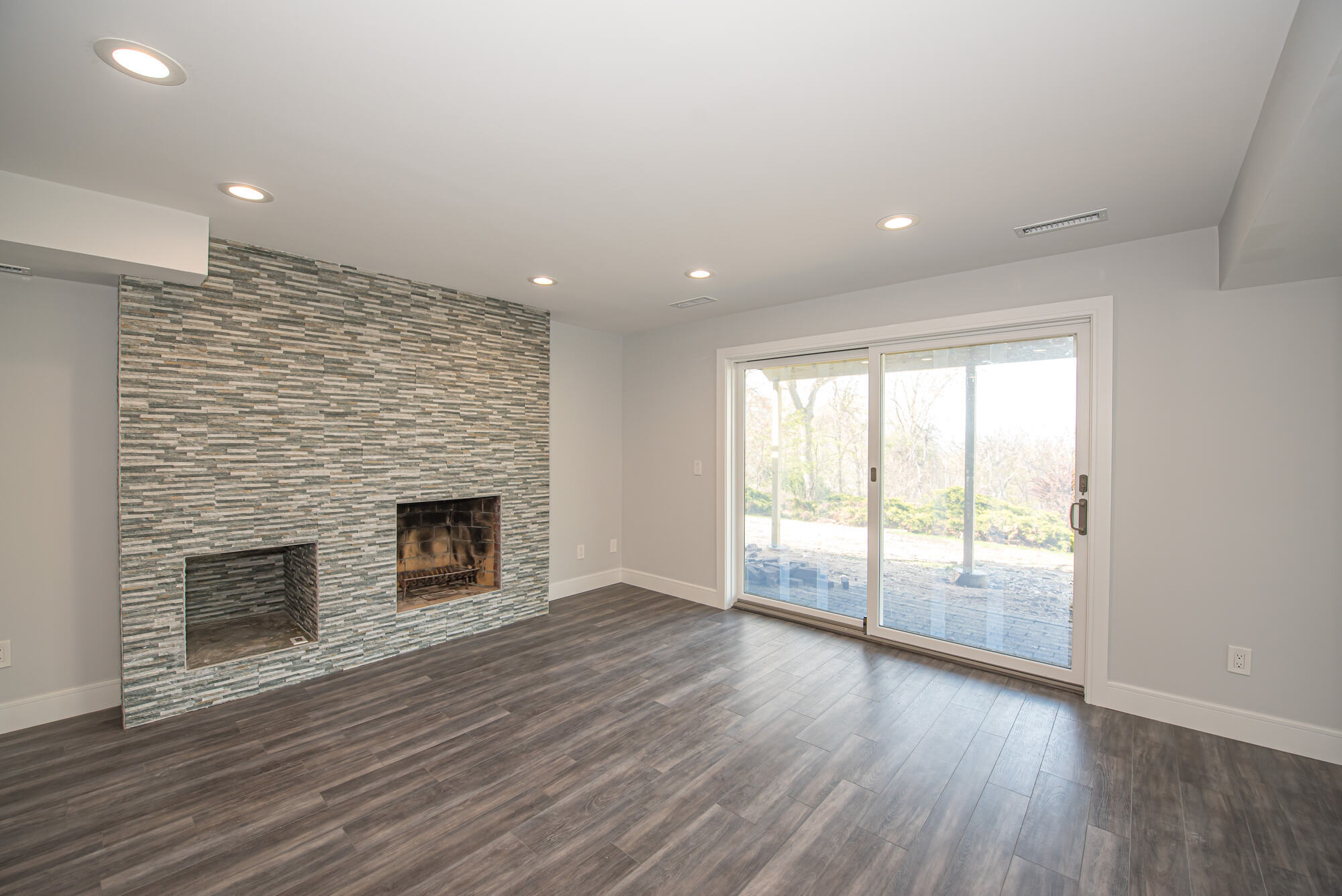 Fireplace feature wall in finished basement with sliding glass doors in Northport, NY custom home