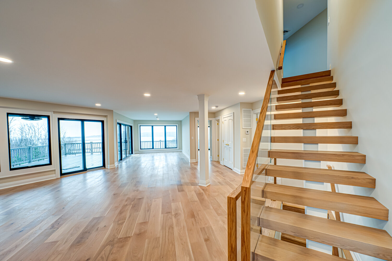 Custom-built living space with natural wood flooring and panoramic glass doors in Miller Place by Long Island Creative Contracting