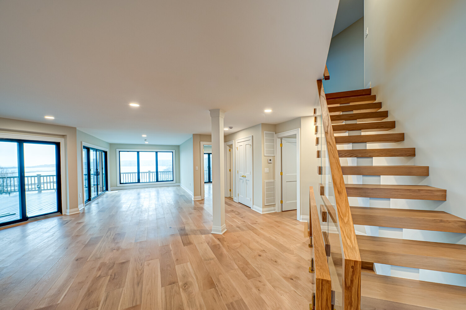 Spacious living room with contemporary staircase in a Long Island Creative Contracting custom home in Miller Place, NY