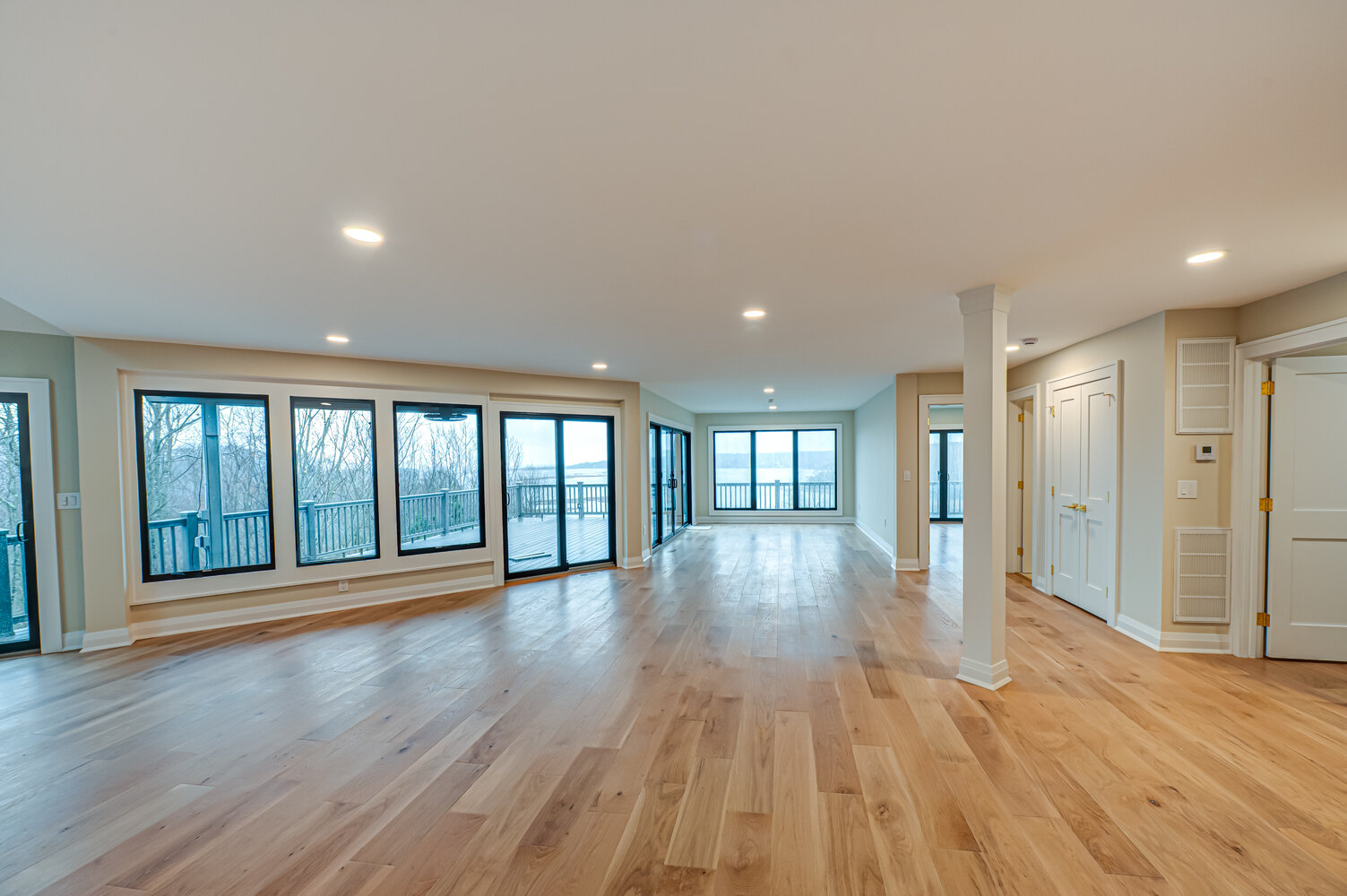 Wide angle of open living area with hardwood flooring and wall of windows in a custom home in Miller Place by Long Island Creative Contracting