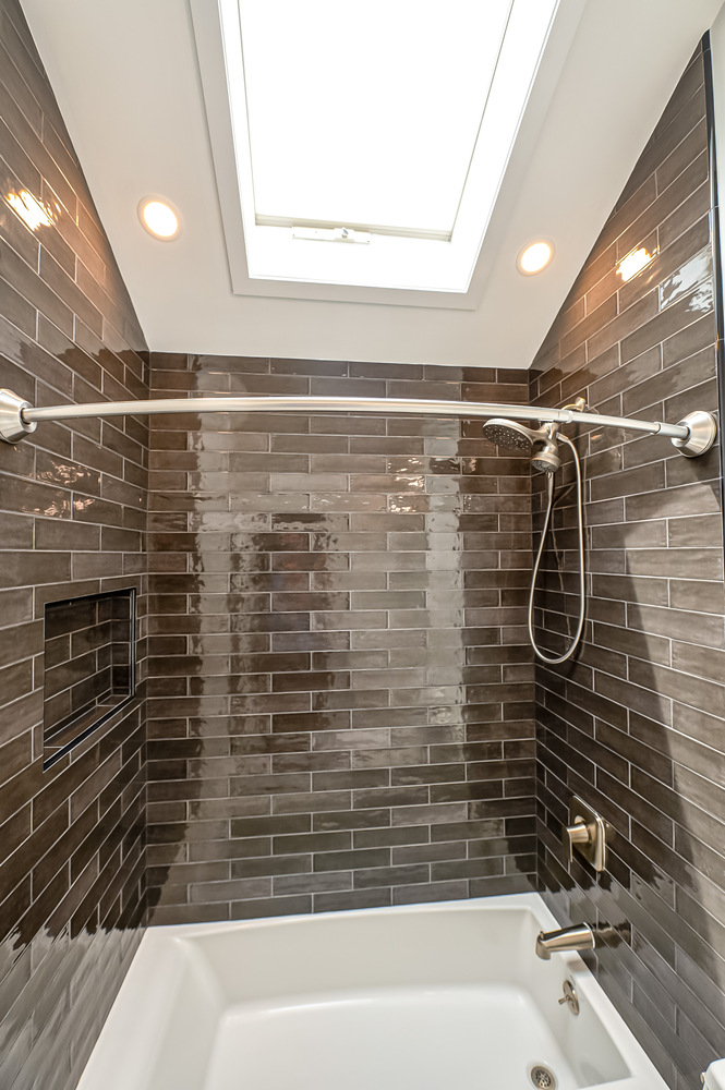 Bright bathroom remodel with skylight and dark tile accent wall in Suffolk County, NY