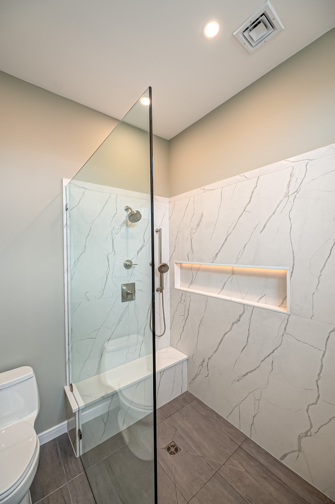 Full view of high-end bathroom with marble tile shower and vanity by Long Island Creative Contracting in Woodbury, NY