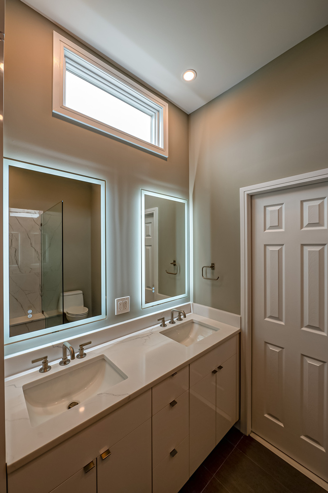 Vertical window above double vanity in sleek bathroom by Long Island Creative Contracting in Suffolk County, NY