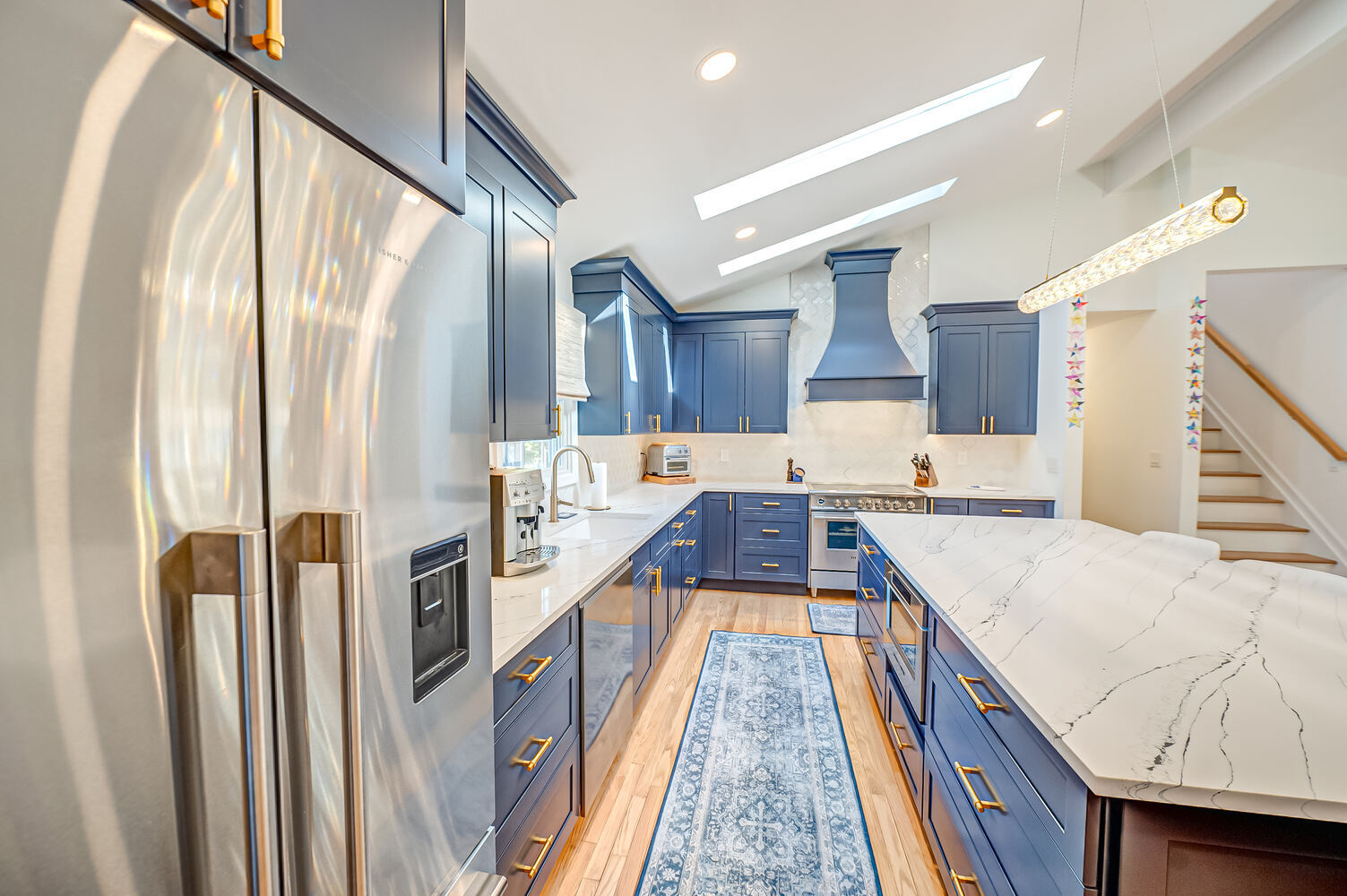 Custom navy kitchen with stainless steel appliances in a Miller Place, NY home by Long Island Creative Contracting, Inc
