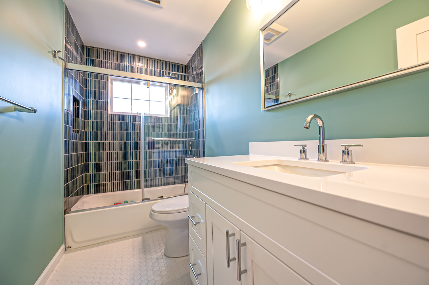 Freshly remodeled bathroom featuring green paint and textured tiles in a Miller Place, NY custom home