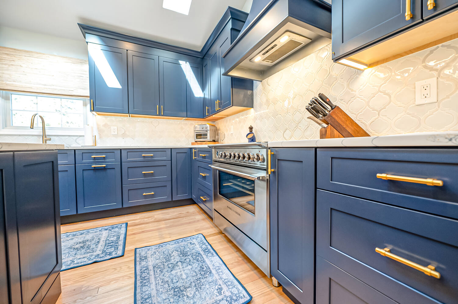 Gourmet kitchen with navy cabinetry and stainless steel range in a Miller Place, NY custom build by Long Island Creative Contracting, Inc