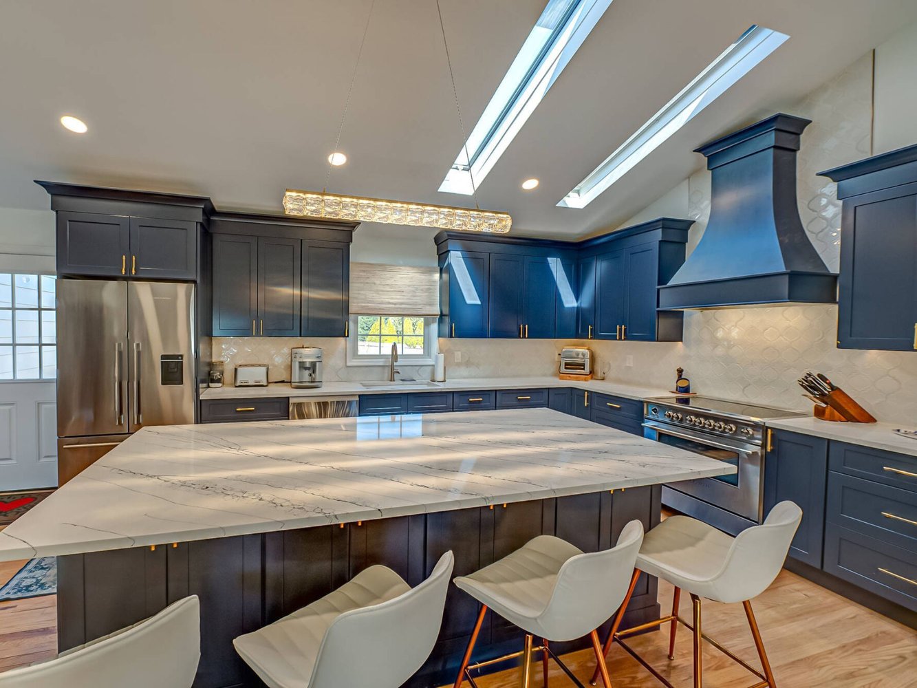 Open kitchen with bold blue cabinetry and white island in a custom build by Long Island Creative Contracting, Inc. in Miller Place, NY