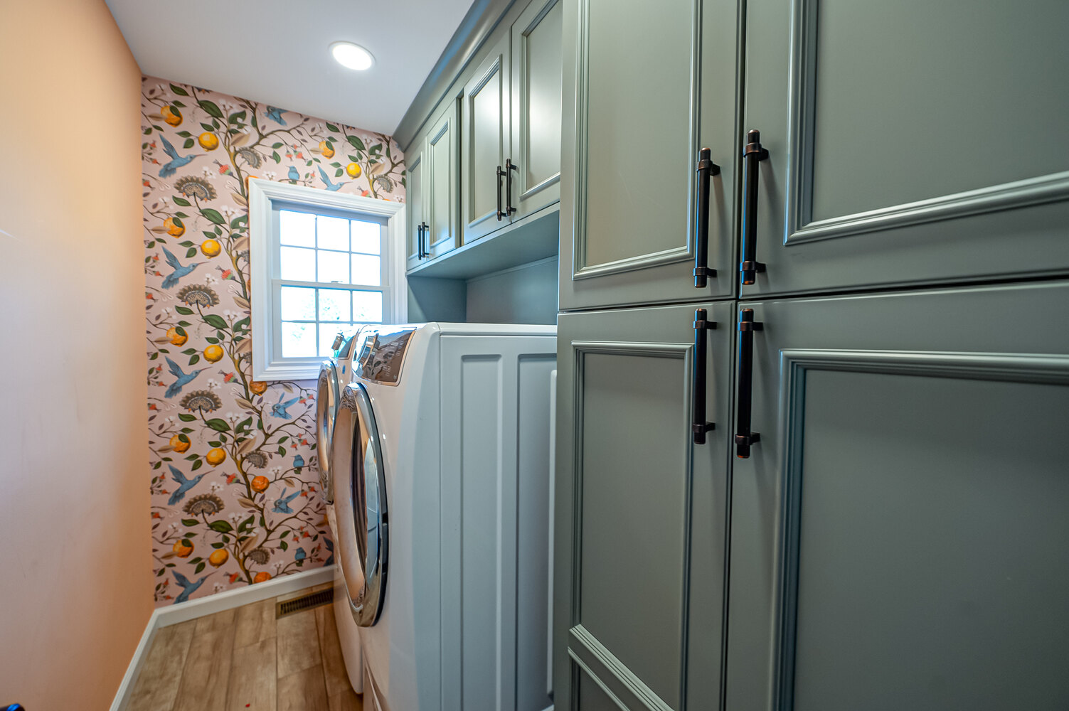 Stylish laundry room with green cabinetry in a custom home by Long Island Creative Contracting, Inc. in Miller Place, NY