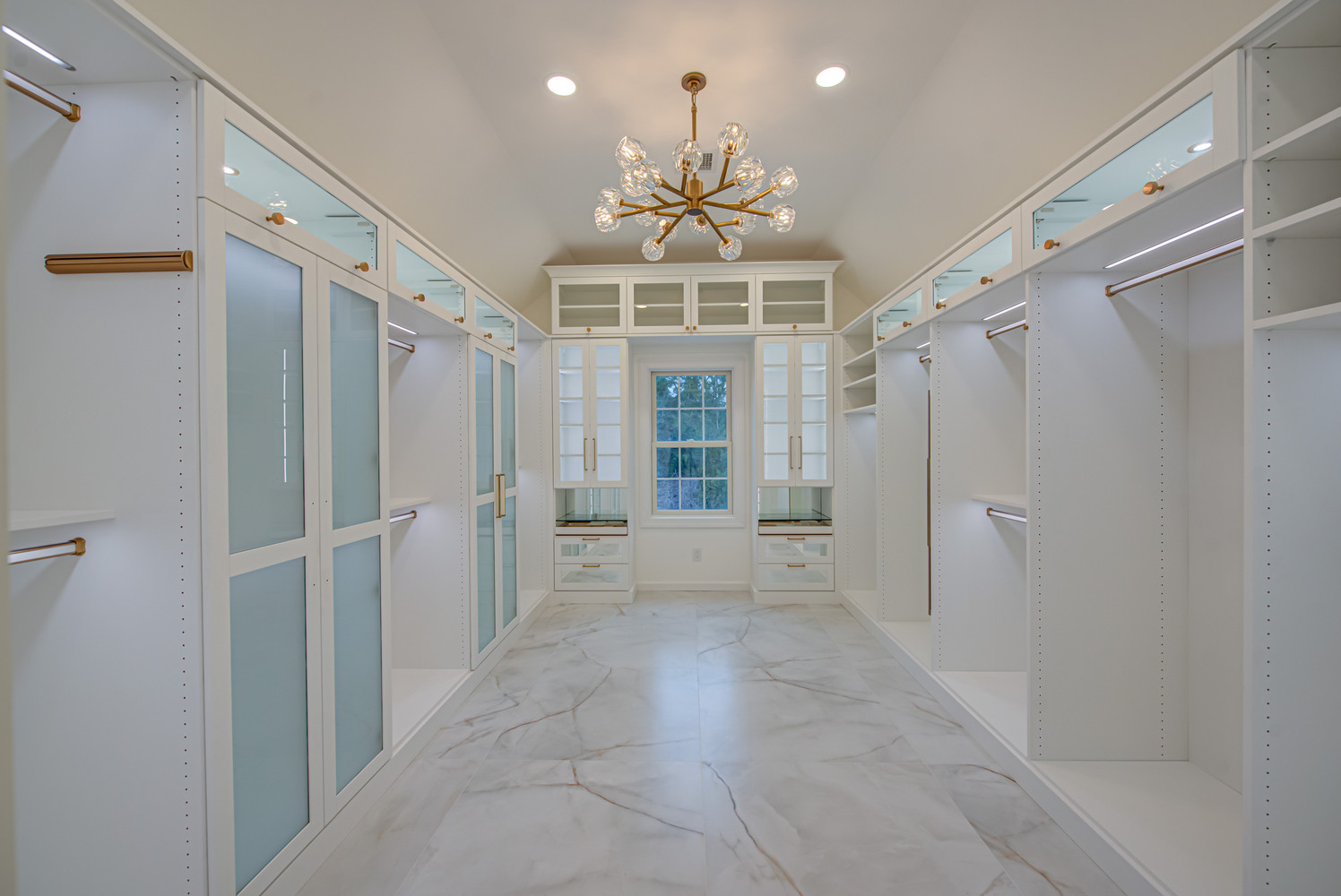Spacious custom walk-in closet with chandelier and built-in shelving by Long Island Creative Contracting, Inc. in Suffolk County, NY