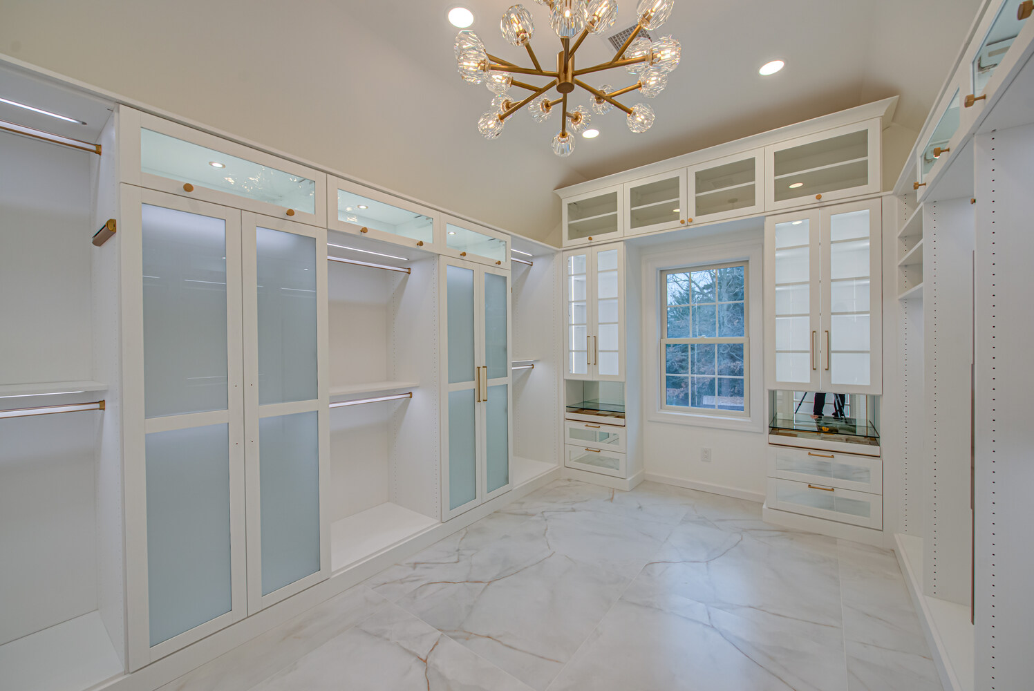 Walk-in closet with built-in vanity and elegant storage by Long Island Creative Contracting, Inc. in Poquott, NY