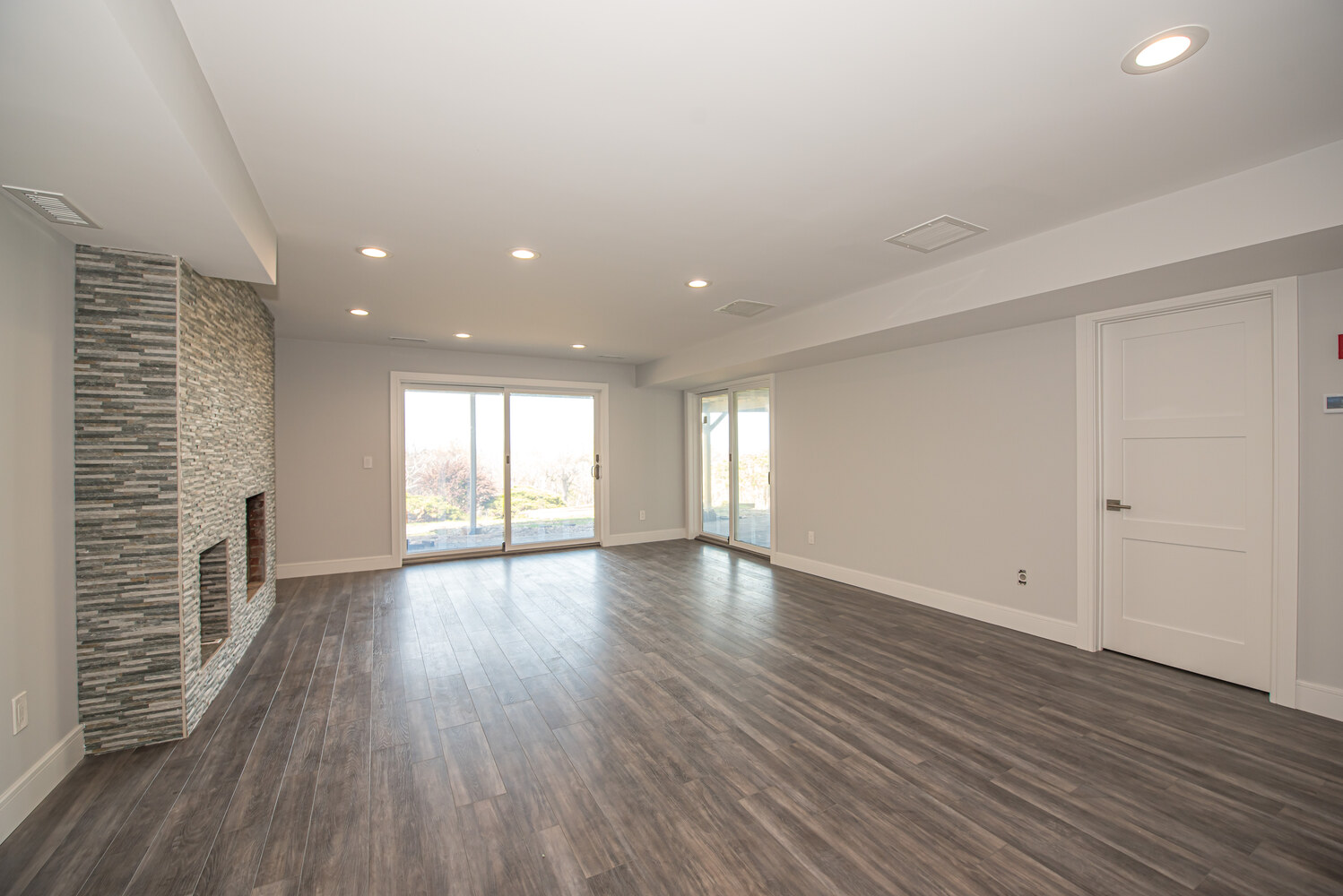 Basement remodel with sliding glass doors and modern flooring in Remsenberg, NY by Long Island Creative Contracting, Inc