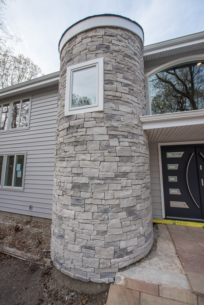 Close-up of curved stone entry tower on a custom home in Mount Sinai NY by Long Island Creative Contracting, Inc