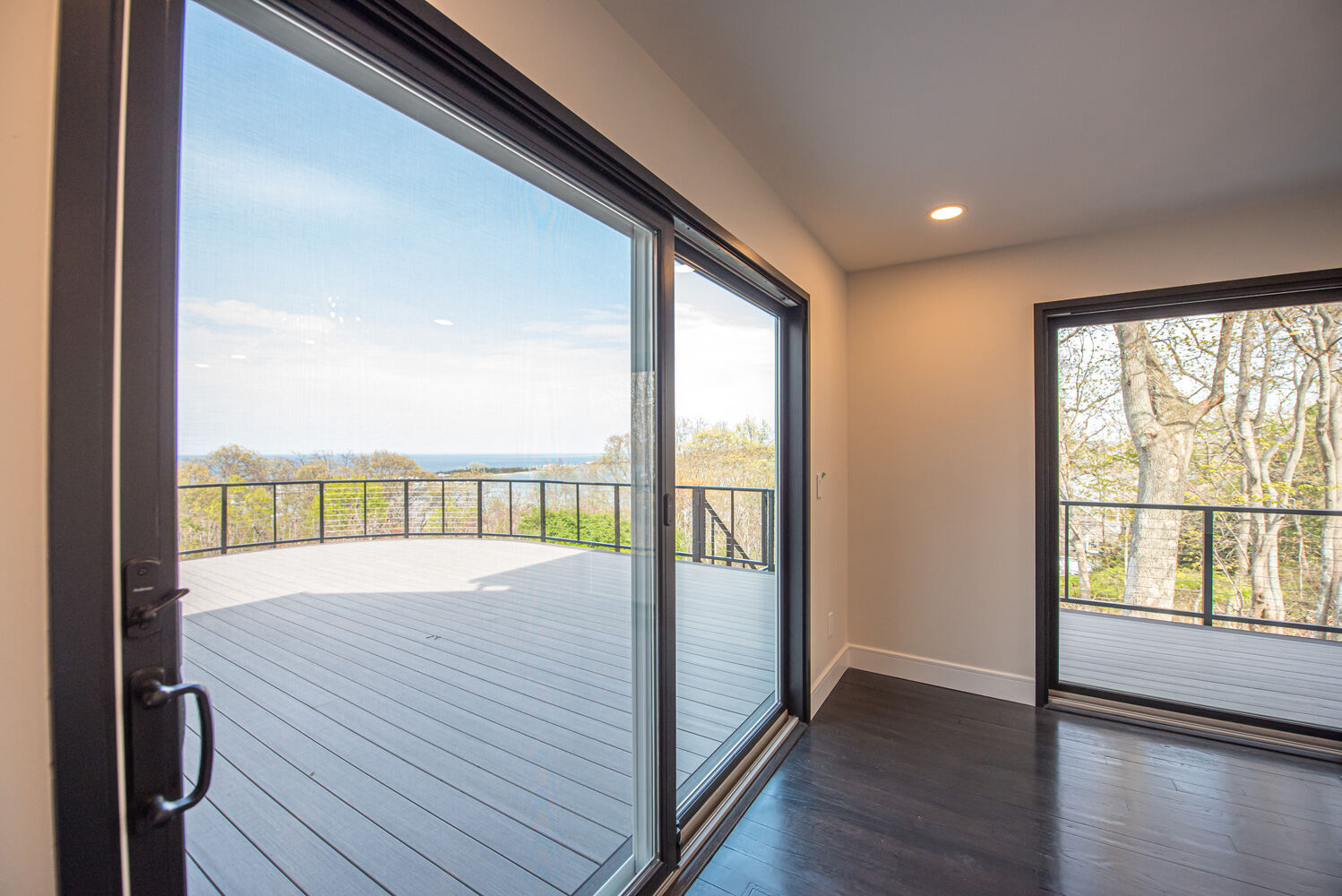 Close-up view of custom deck and waterfront landscape through sliding doors in Three Villages, NY by Long Island Creative Contracting, Inc