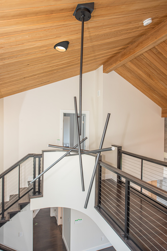 Contemporary chandelier and loft walkway in a Setauket NY custom home by Long Island Creative Contracting, Inc