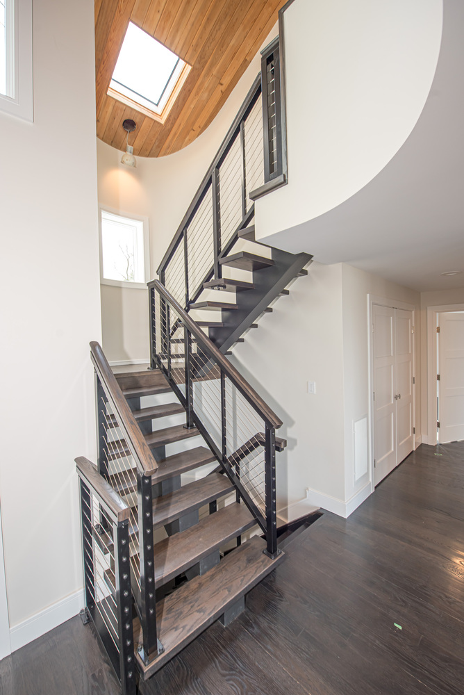 Contemporary staircase with open treads and cable railing beneath wood-paneled ceiling in Port Jefferson, NY by Long Island Creative Contracting, Inc