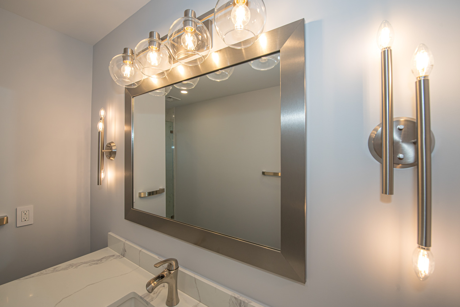 Custom bathroom vanity with brushed nickel fixtures and modern lighting in Port Jefferson, NY by Long Island Creative Contracting, Inc