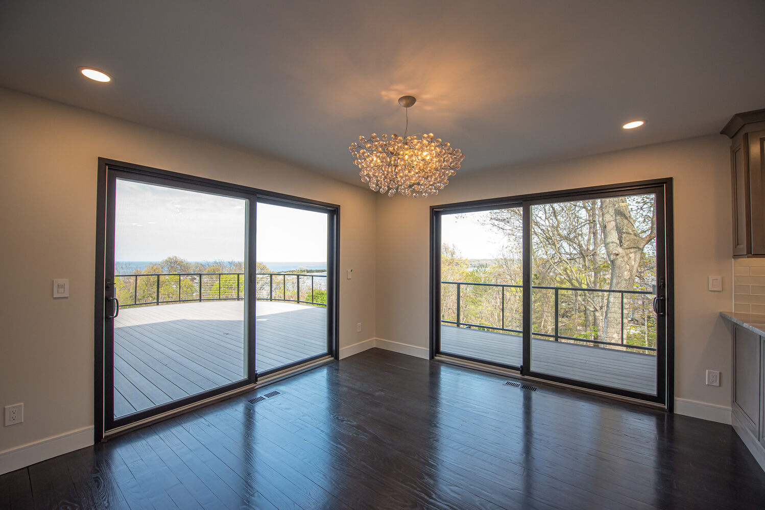 Dining area with panoramic water views and glass sliding doors in Woodbury, NY by Long Island Creative Contracting, Inc
