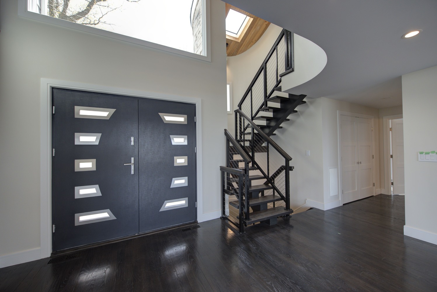 Entryway with modern staircase and large front doors in a Three Villages, NY custom home by Long Island Creative Contracting, Inc