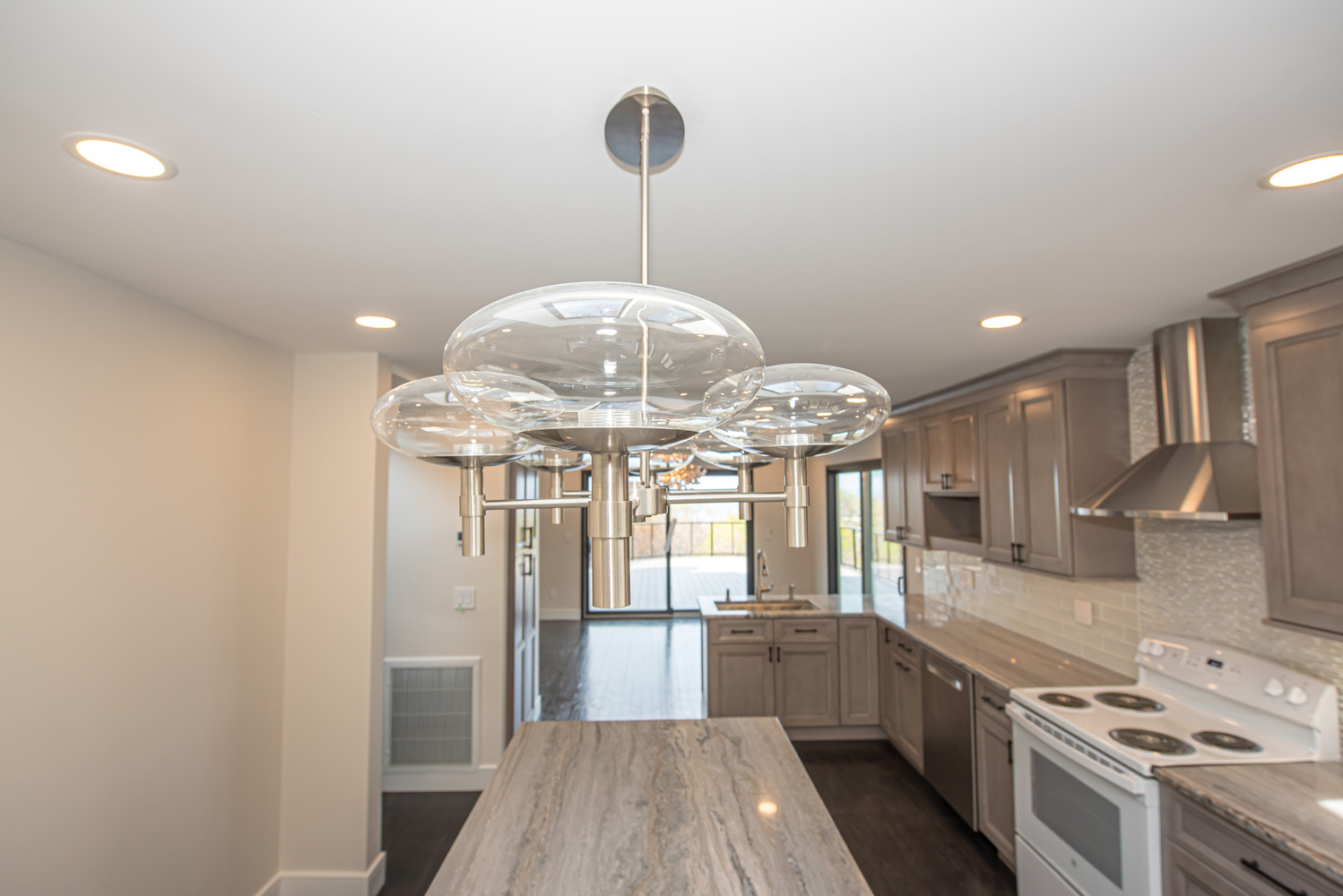 Kitchen view highlighting modern glass pendant light fixture and center island in Poquott, NY by Long Island Creative Contracting, Inc