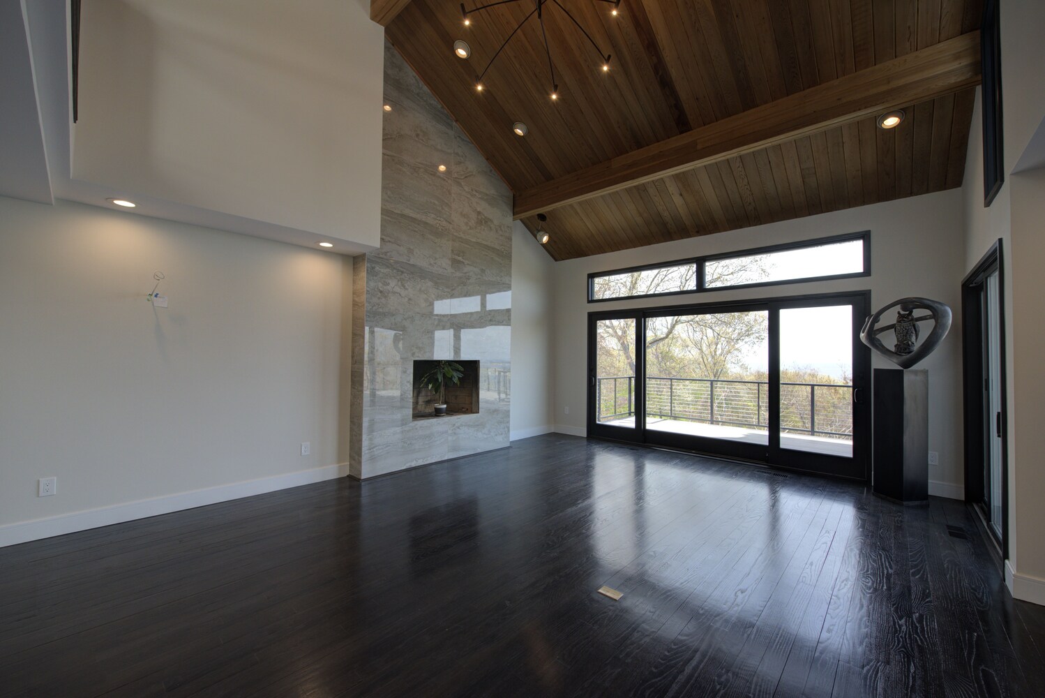 Light-filled living room with vaulted wood ceiling and marble fireplace by Long Island Creative Contracting, Inc., Port Jefferson, NY