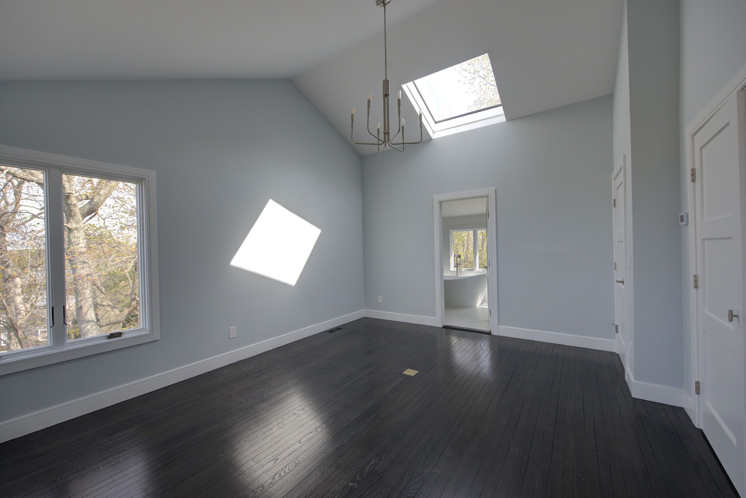 Light-filled master bedroom with modern chandelier by Long Island Creative Contracting, Inc., Huntington, NY