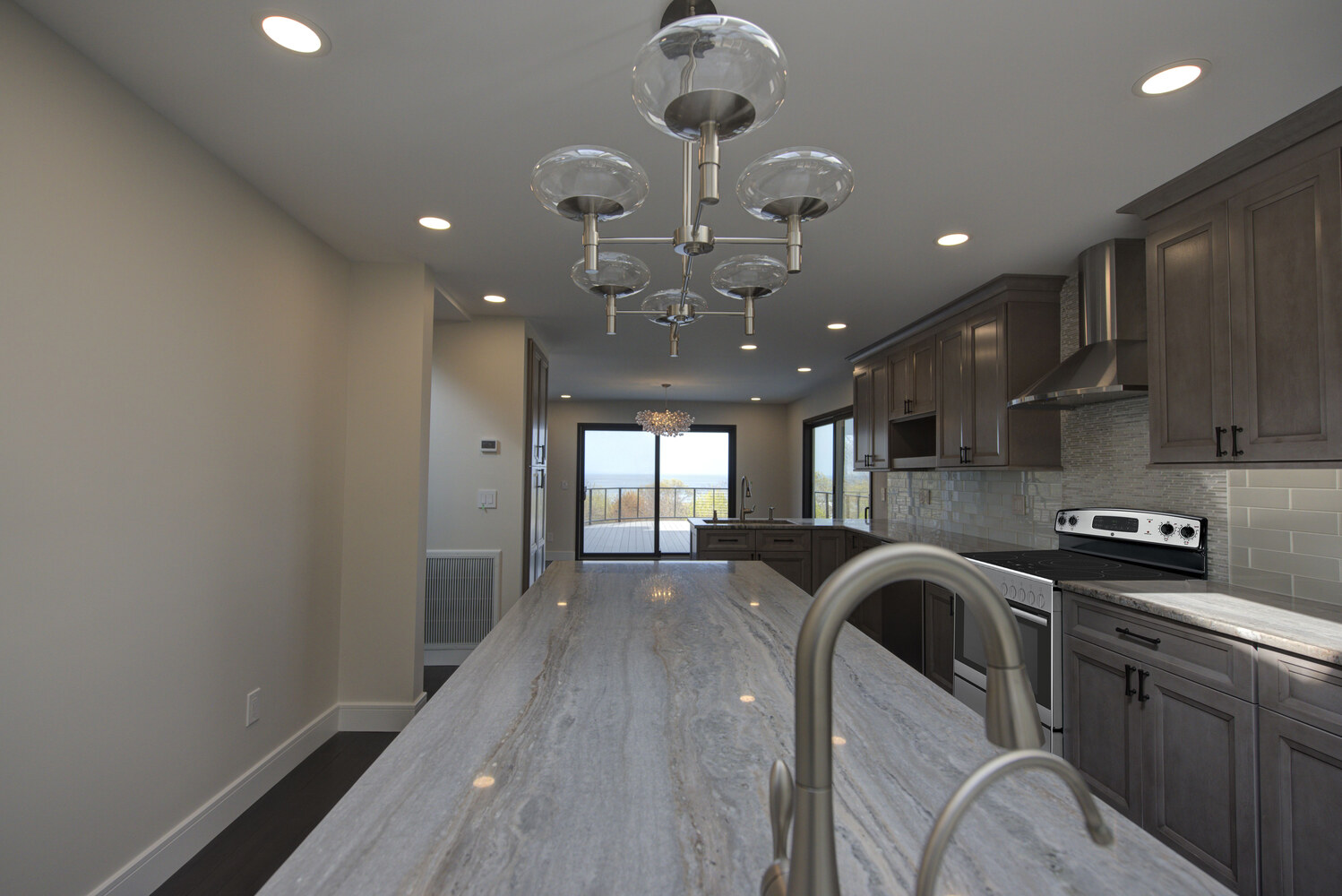 Long custom kitchen island with stainless fixtures by Long Island Creative Contracting, Inc. in Miller Place, NY