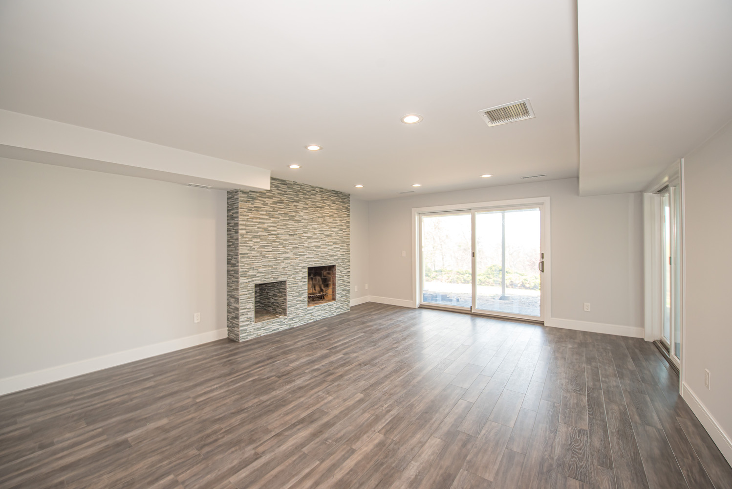 Modern custom basement with accent wall and patio access in Port Jefferson Station, NY