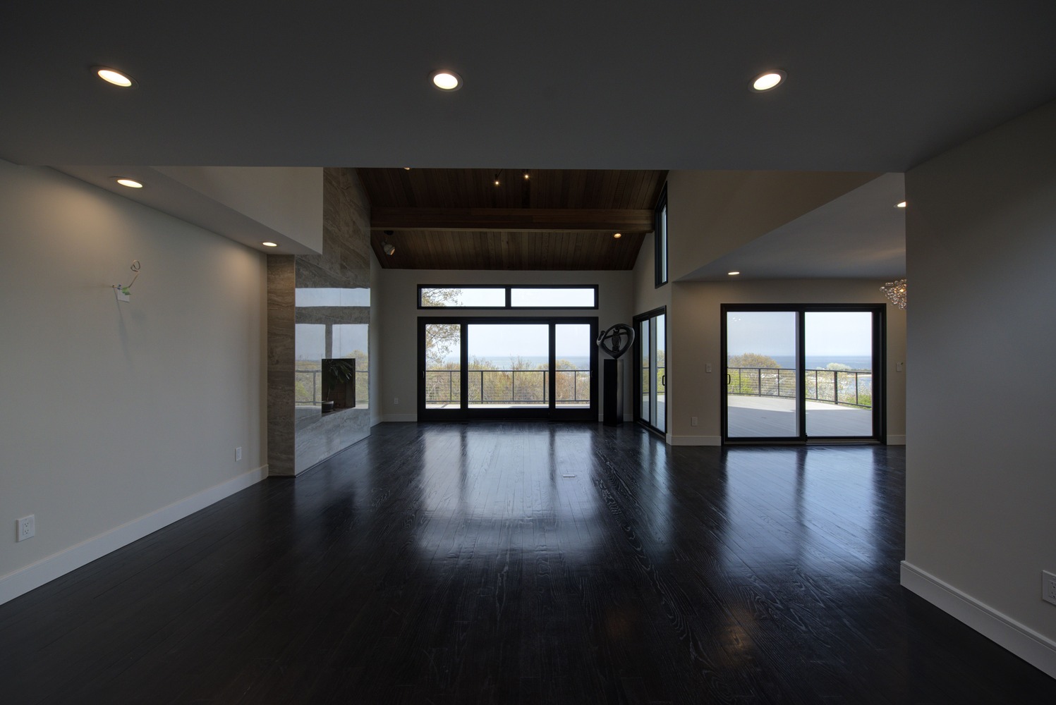 Open living room with wood ceiling and wall of windows in a custom build by Long Island Creative Contracting, Inc., East Setauket, NY