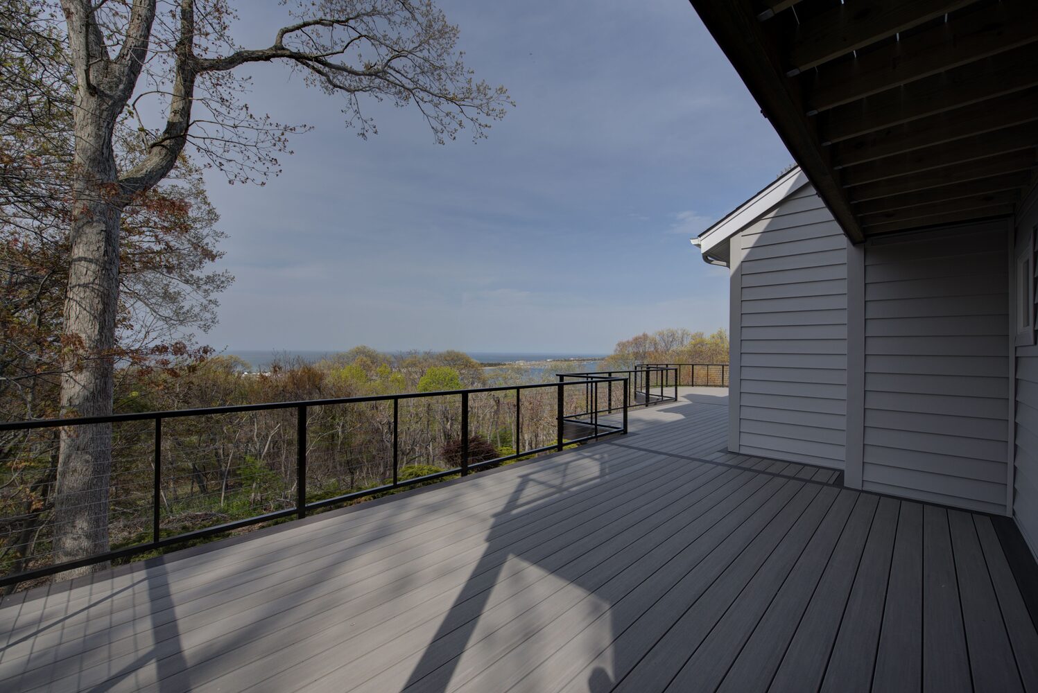 Rear deck surrounded by trees in a custom home in Suffolk County, NY by Long Island Creative Contracting, Inc