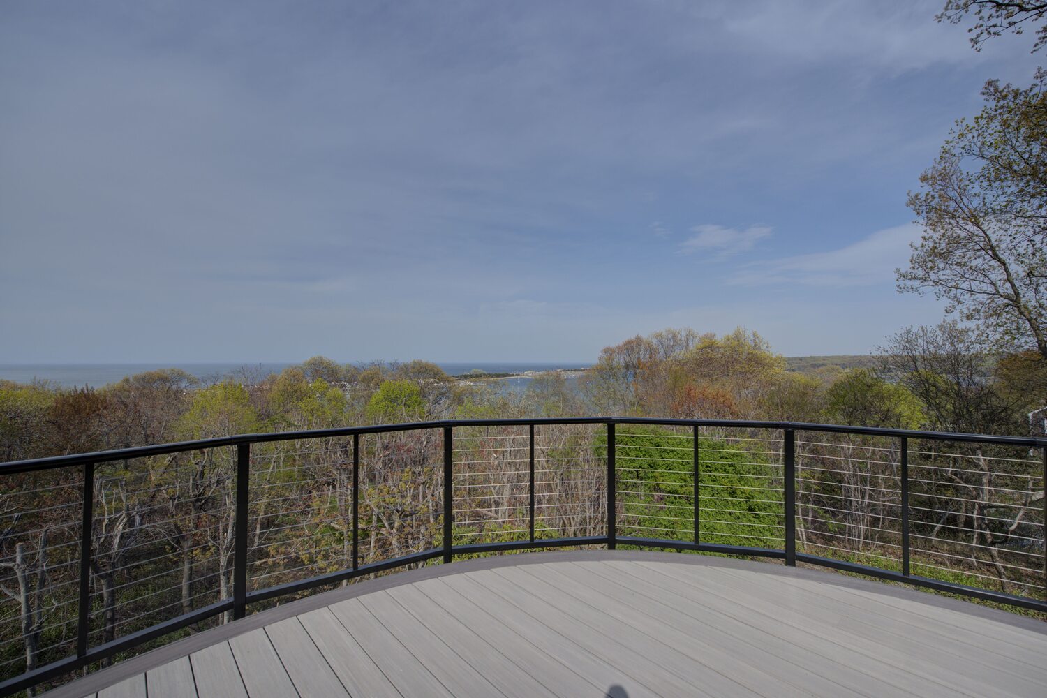 Rear view of modern custom home with expansive composite decking in Port Jefferson Station, NY