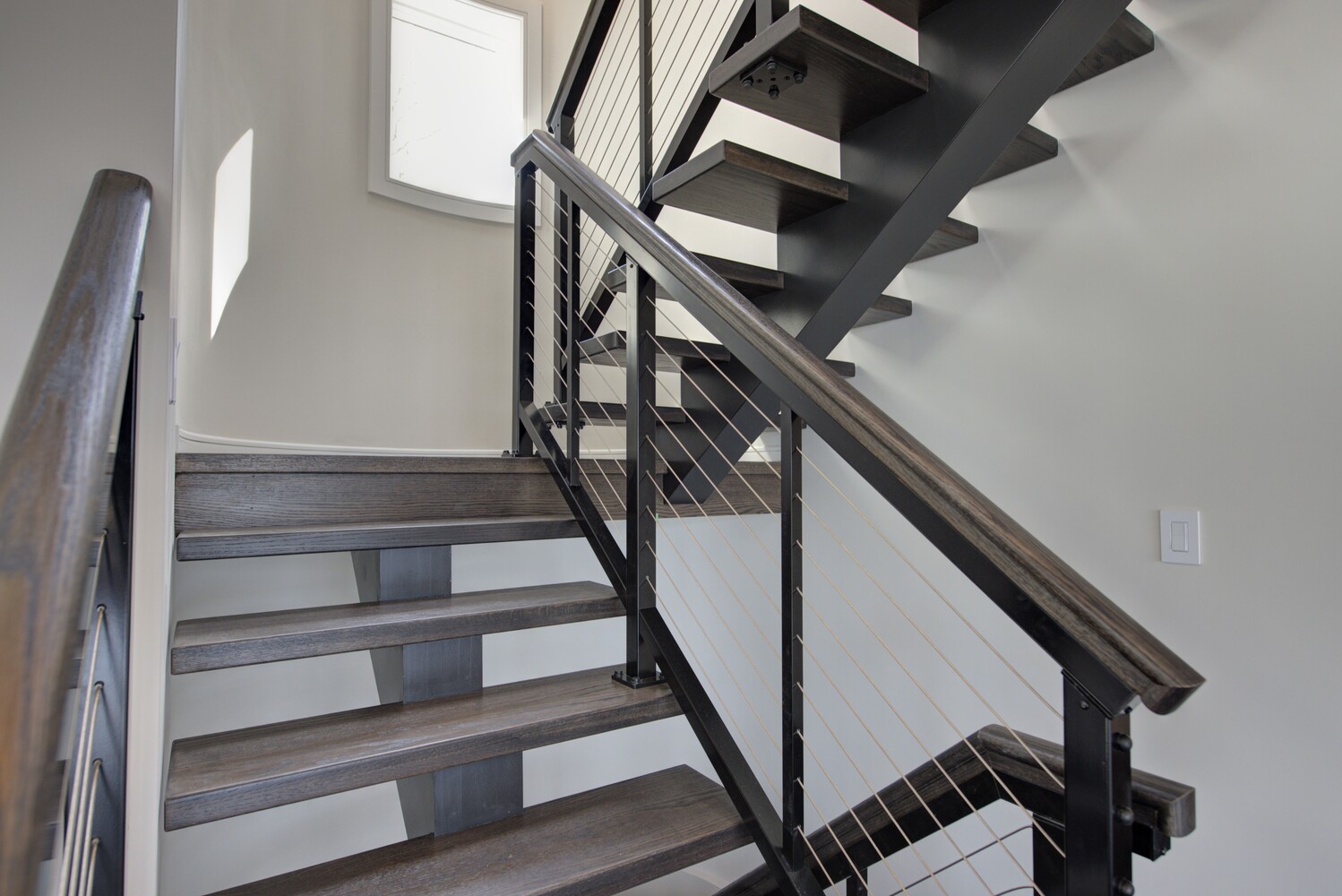 Stylish dark wood and black metal stairs in a Three Villages, NY custom home by Long Island Creative Contracting, Inc