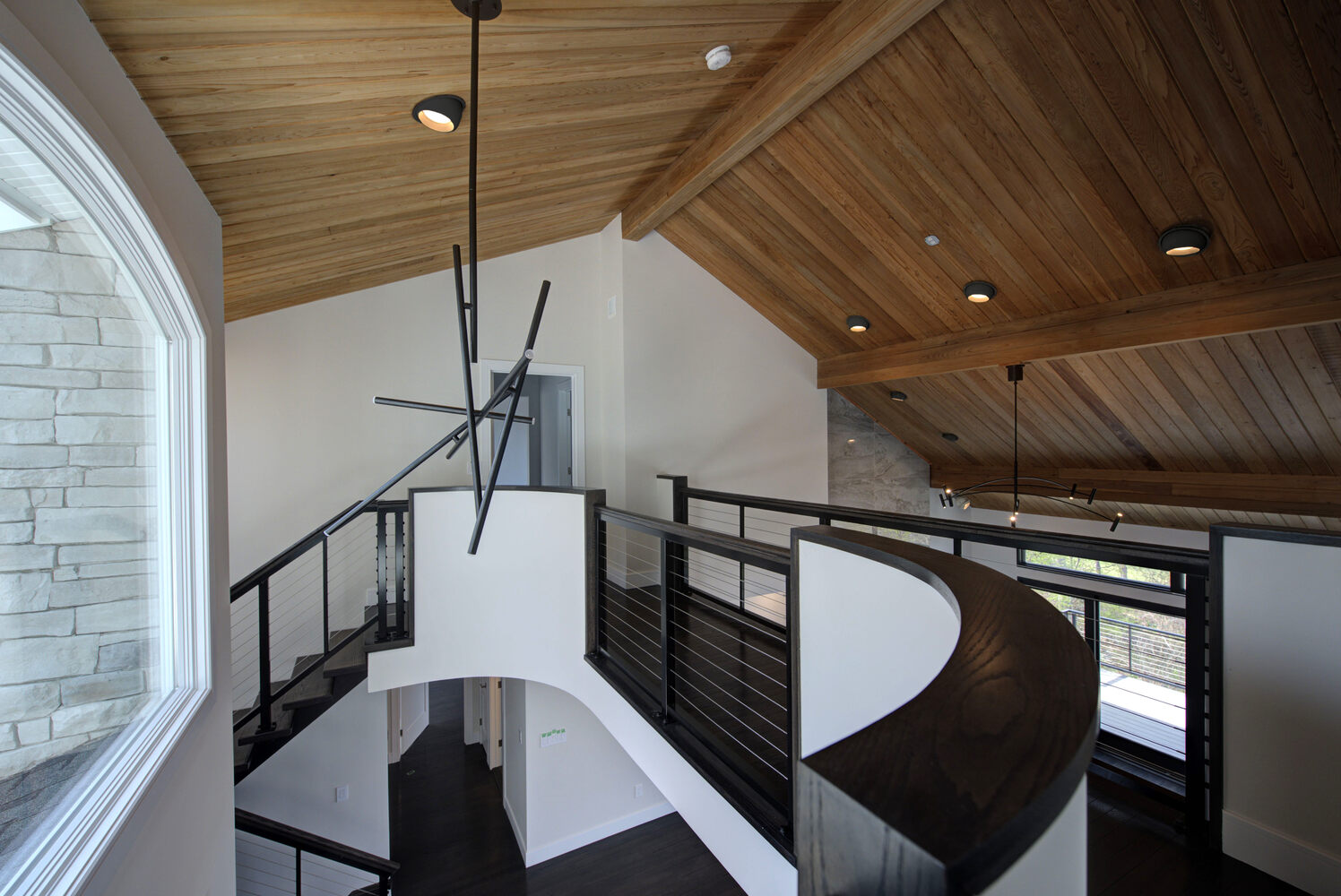 Upper landing with curved railing and vaulted ceiling by Long Island Creative Contracting, Inc., Suffolk County, NY