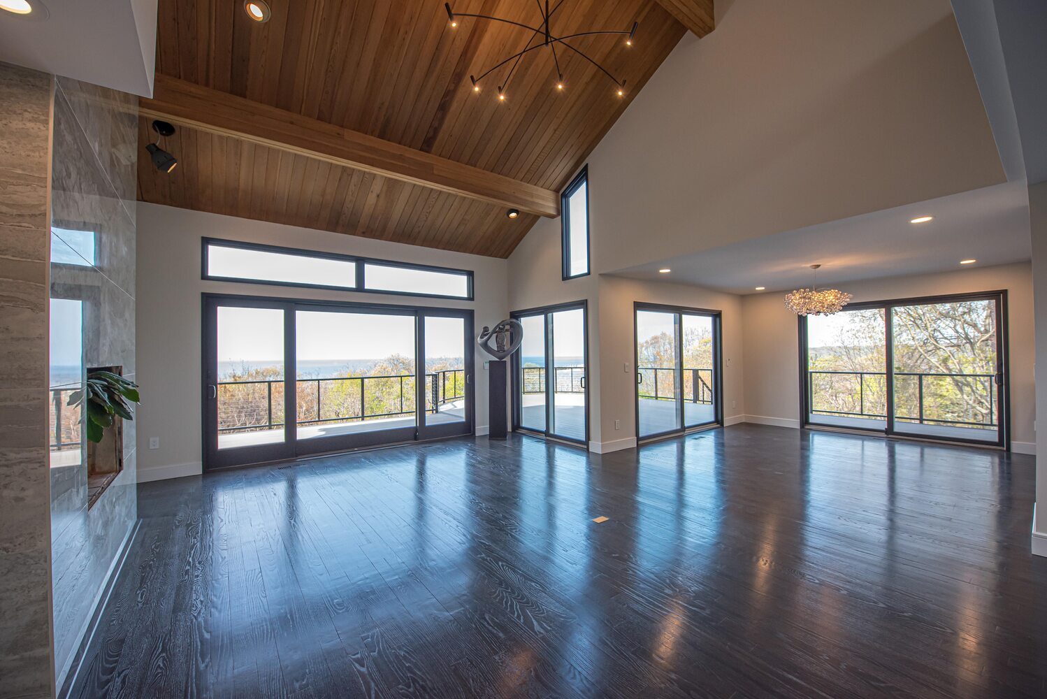 Vaulted ceiling living area with wood paneling and ocean views in Setauket, NY by Long Island Creative Contracting, Inc