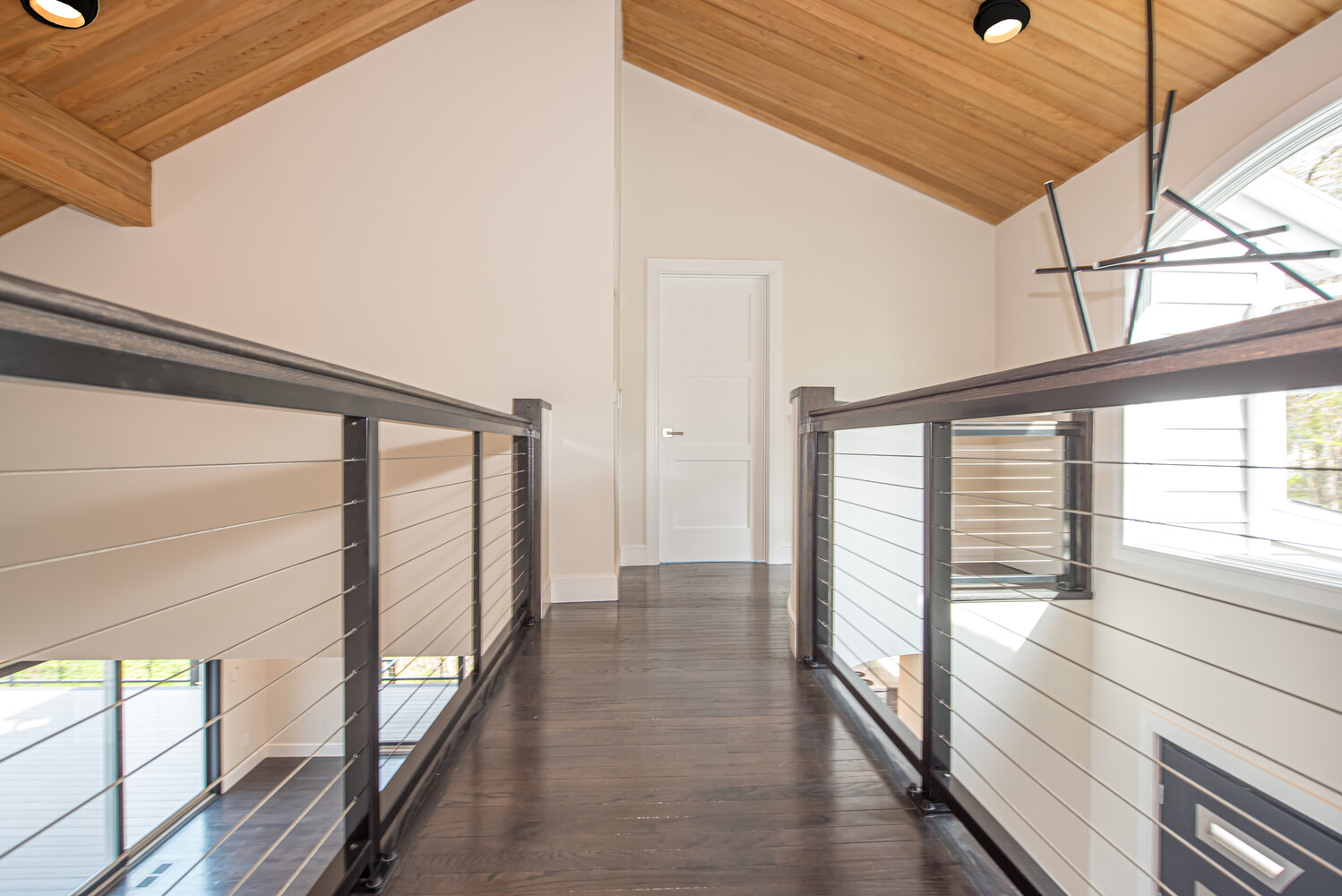 Walkway with metal railing on upper floor of a custom home by Long Island Creative Contracting, Inc. in Port Jefferson NY
