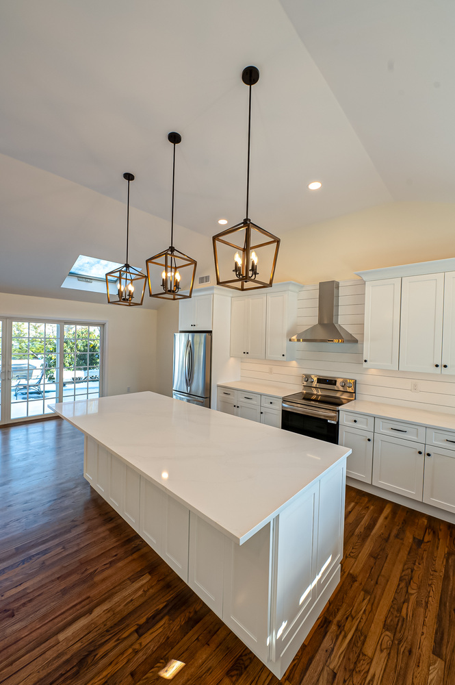 Large kitchen island and sliding doors in a Poquott custom home by Long Island Creative Contracting, Inc
