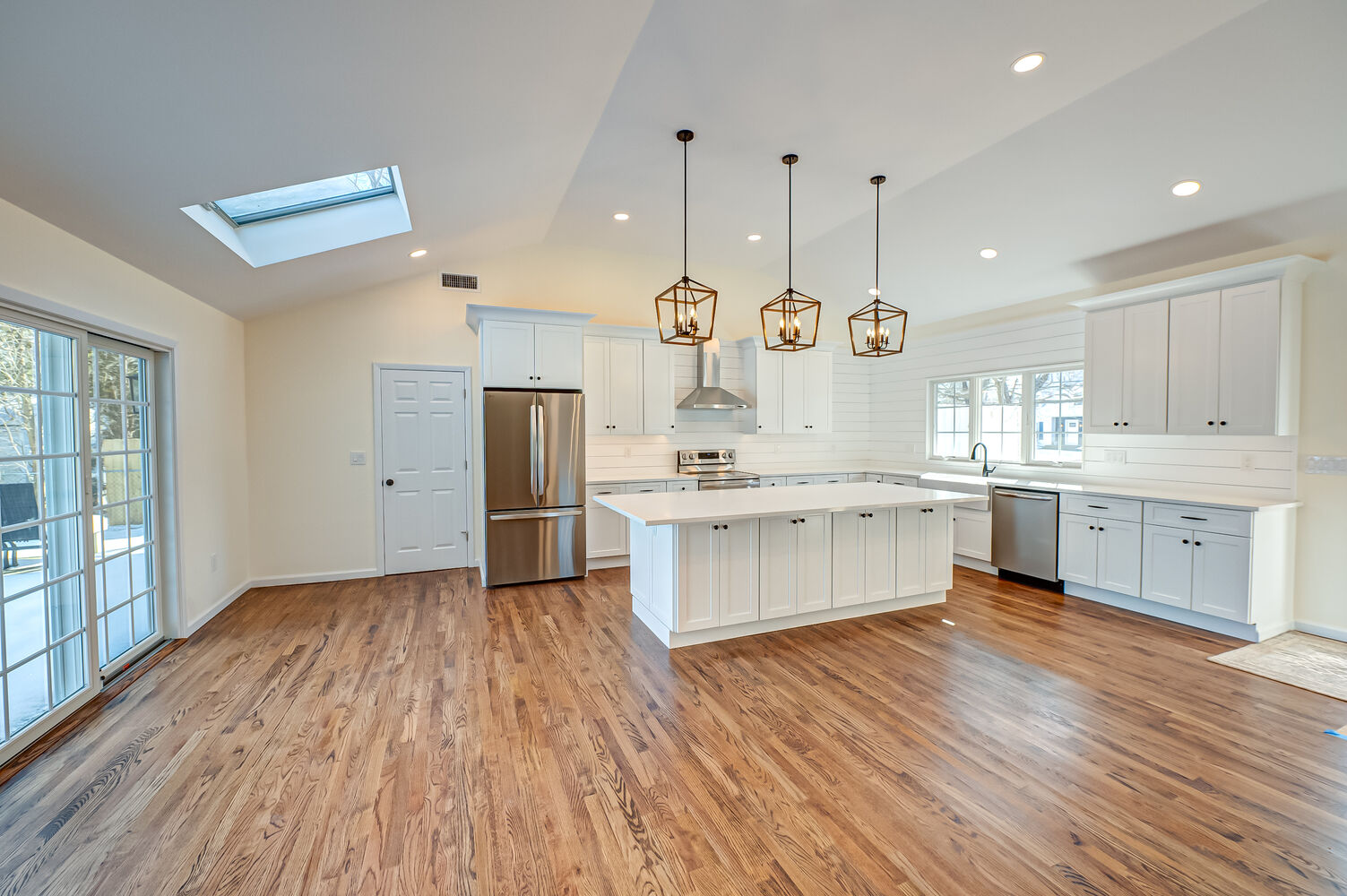 Open kitchen and dining layout with fan and white trim in a remodeled Huntington, NY home by Long Island Creative Contracting