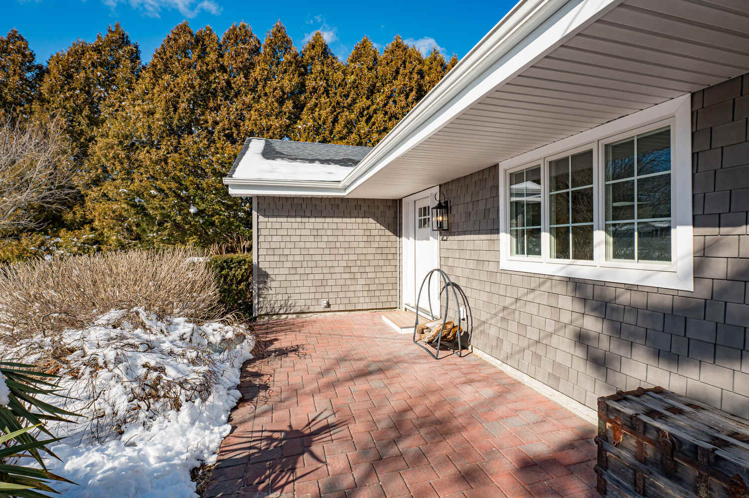 Snow-lined brick patio and siding detail on a custom home in Miller Place, NY
