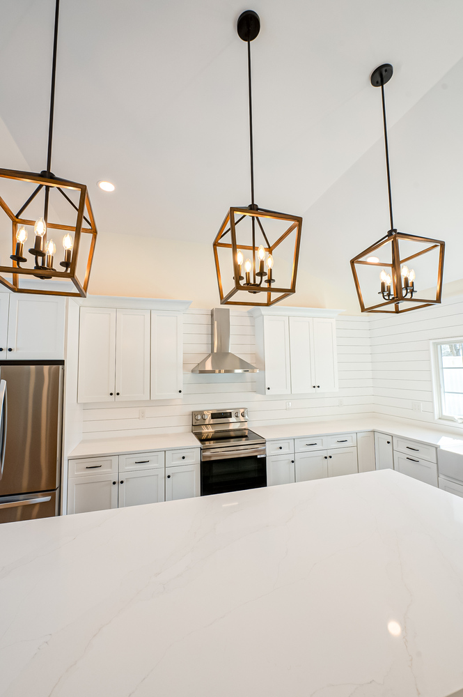 Transitional kitchen design with large quartz island and pendant lights in an East Setauket custom build