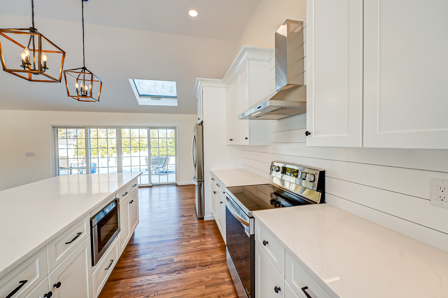 White kitchen with range hood and natural wood floors by Long Island Creative Contracting in Woodbury, NY
