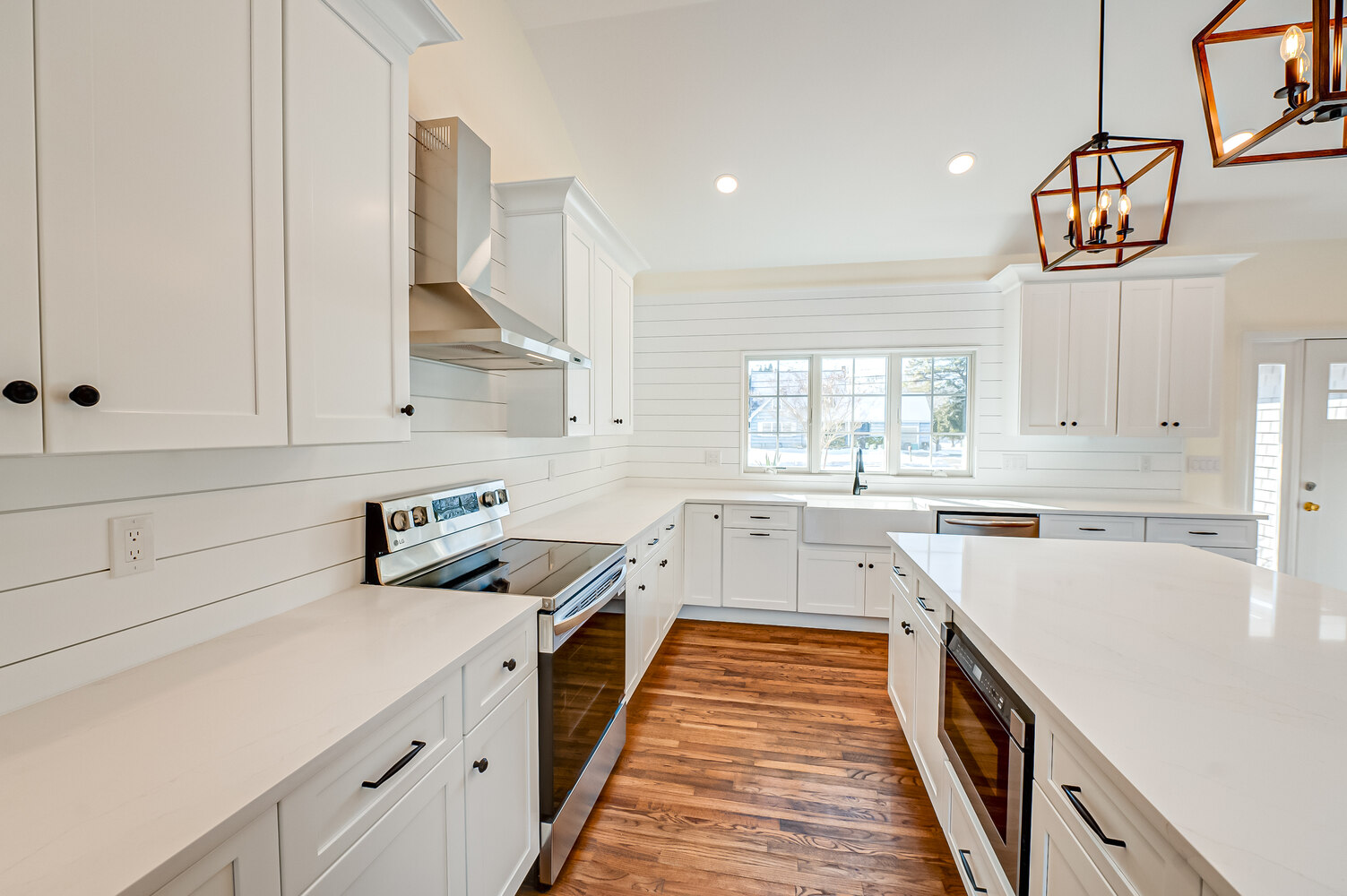 Wide-angle kitchen view with island seating and pendant lighting by Long Island Creative Contracting in Setauket, NY