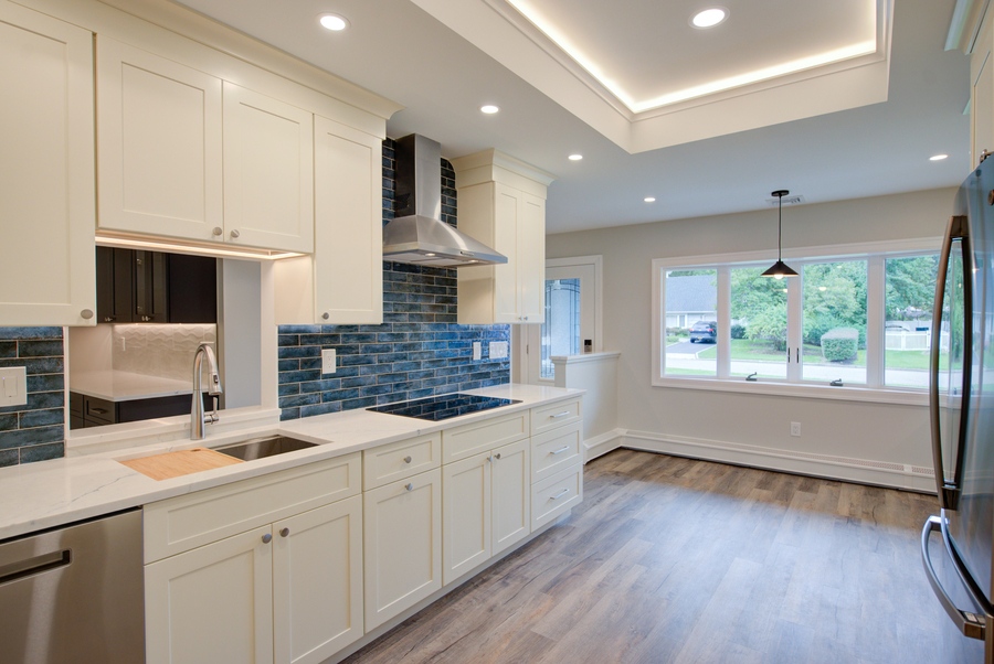 Bright custom kitchen with large picture window and blue accent tile in a Remsenberg, NY home