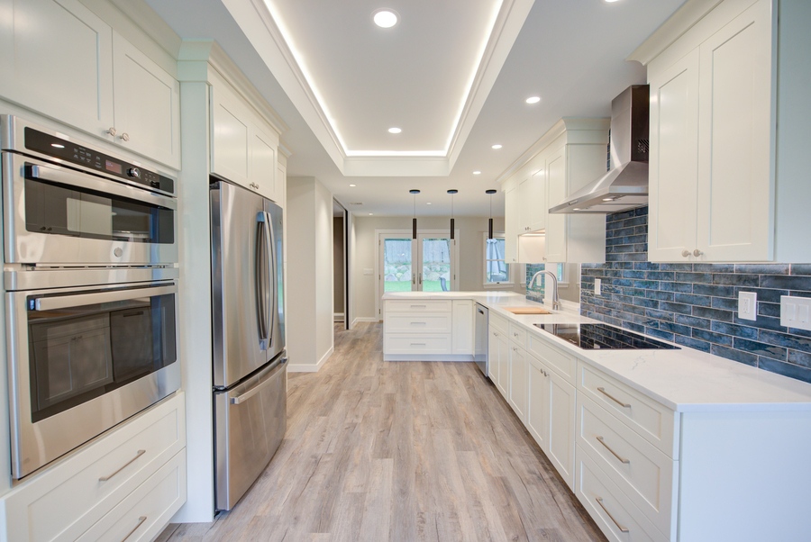 Clean white kitchen design with blue tile accent wall in a Northport, NY custom renovation Clean white kitchen design with blue tile accent wall in a Northport, NY custom renovation