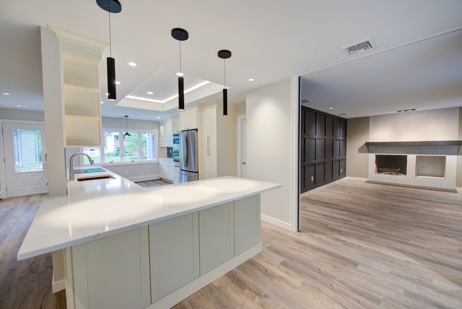 Kitchen island and open view into modern living room with fireplace in a Stony Brook, NY custom home