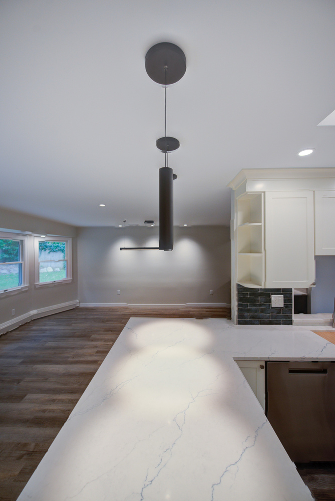 Marble kitchen island with pendant lighting in a custom Suffolk County home by Long Island Creative Contracting, Inc