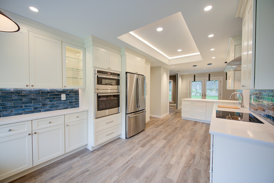 Modern kitchen featuring stainless appliances and white shaker cabinetry in a Poquott, NY home remodel