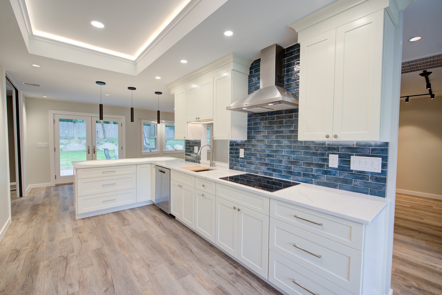 Modern kitchen with stainless vent hood and blue subway tile backsplash by Long Island Creative Contracting in Setauket, NY
