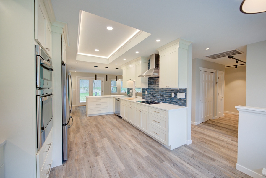 Open kitchen layout with white cabinetry and blue accent tile by Long Island Creative Contracting in Stony Brook, NY