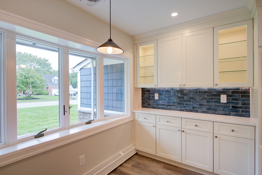 Upper glass cabinets and blue backsplash highlight this Long Island Creative Contracting, Inc. kitchen in Suffolk County