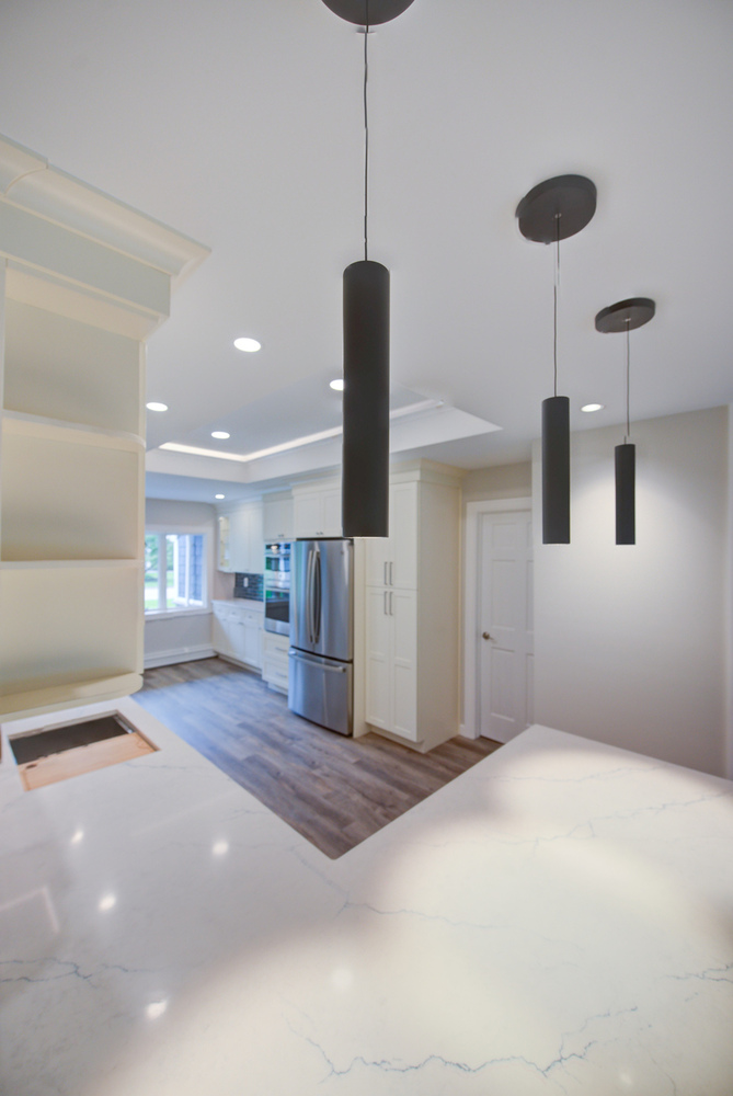 Wide-angle kitchen view with wood floors and quartz countertops in a Woodbury, NY custom build