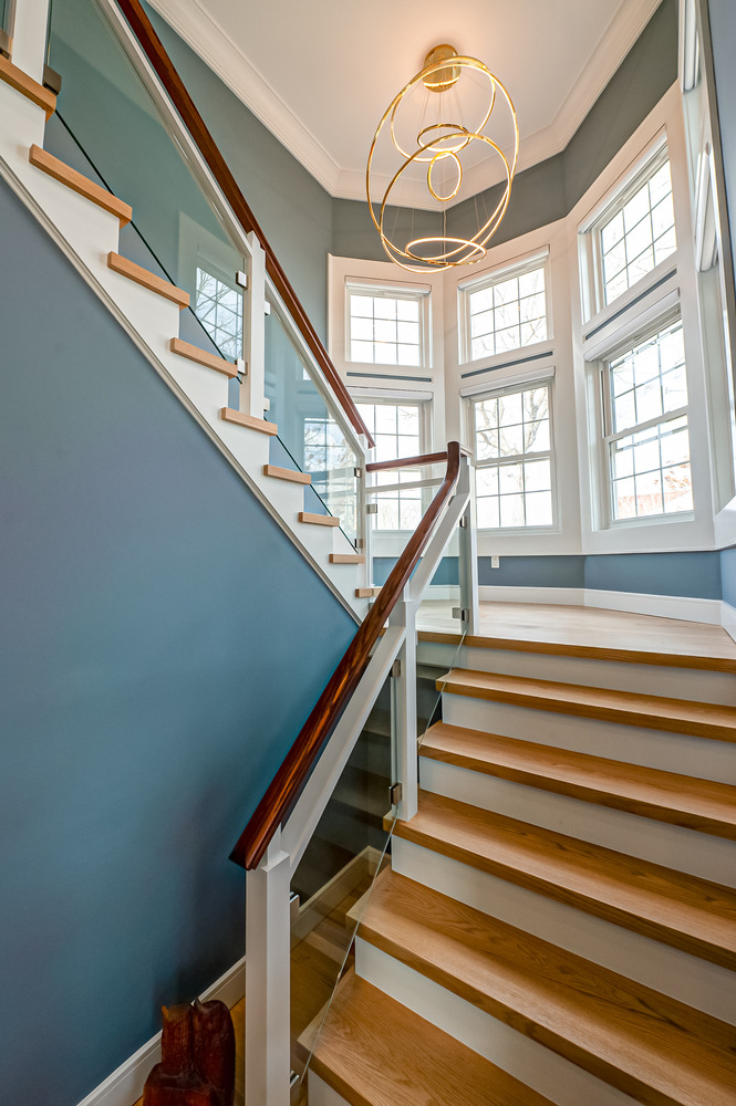 Sleek staircase with glass railing and modern lighting in Mount Sinai, NY custom home by Long Island Creative Contracting, Inc